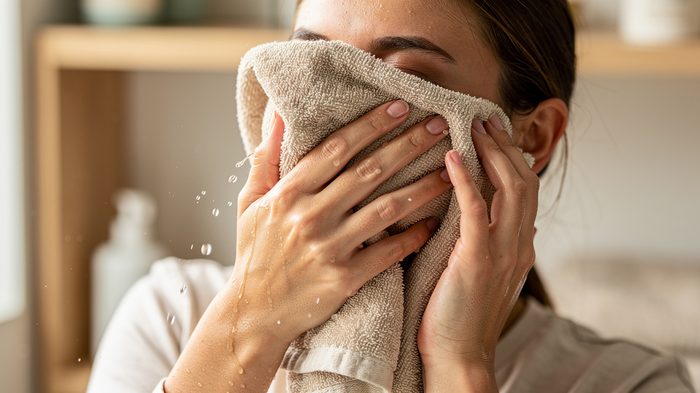 Kadın yüzünü sert bir havluyla yıkıyor, banyo